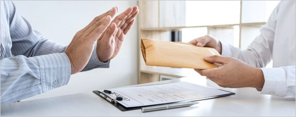 Personne refusant une enveloppe qu'une autre personne lui tend en mettant ses deux mains en avant.